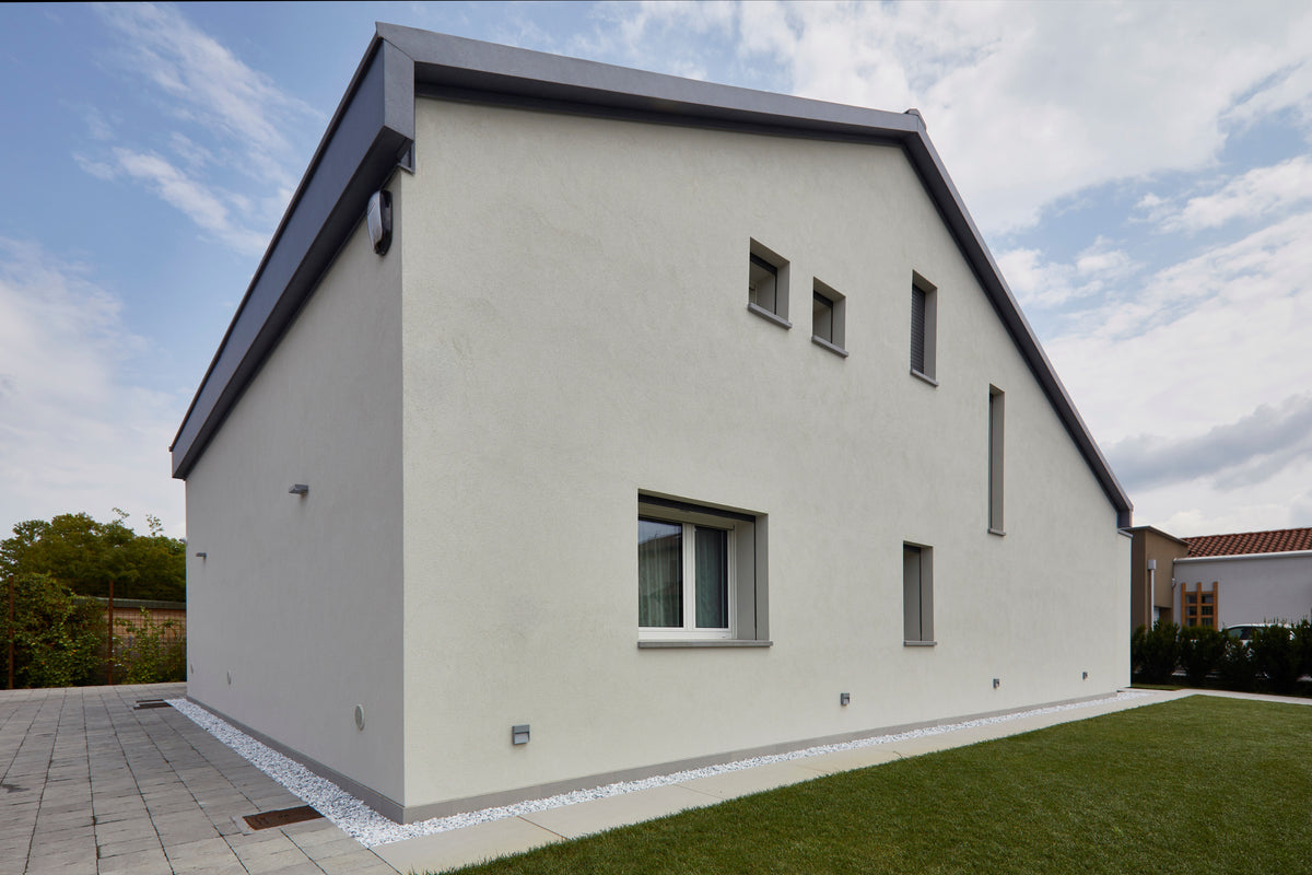 Architettura esterna della casa con volumi essenziali, facciata chiara e aperture verticali