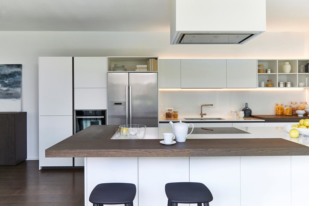 Composizione cucina lineare con isola, cappa centrale, pensili bianchi e piano snack con top in legno scuro a contrasto