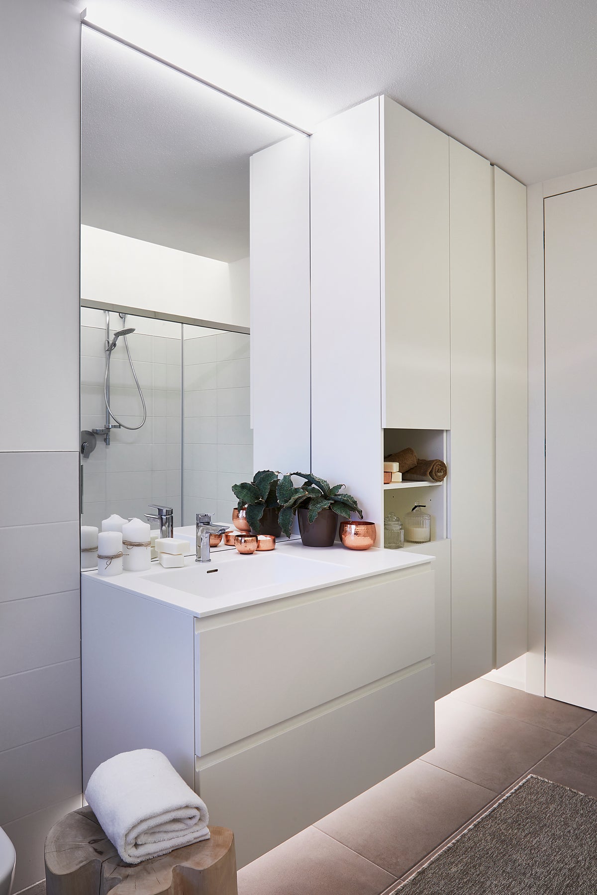 Bagno moderno con mobile lavabo sospeso e lavello integrato, armadiatura su misura, illuminazione perimetrale e design essenziale