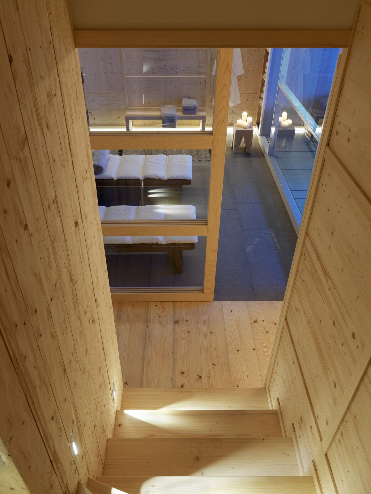 Scala interna in legno con illuminazione integrata che porta allo spazio wellness privato