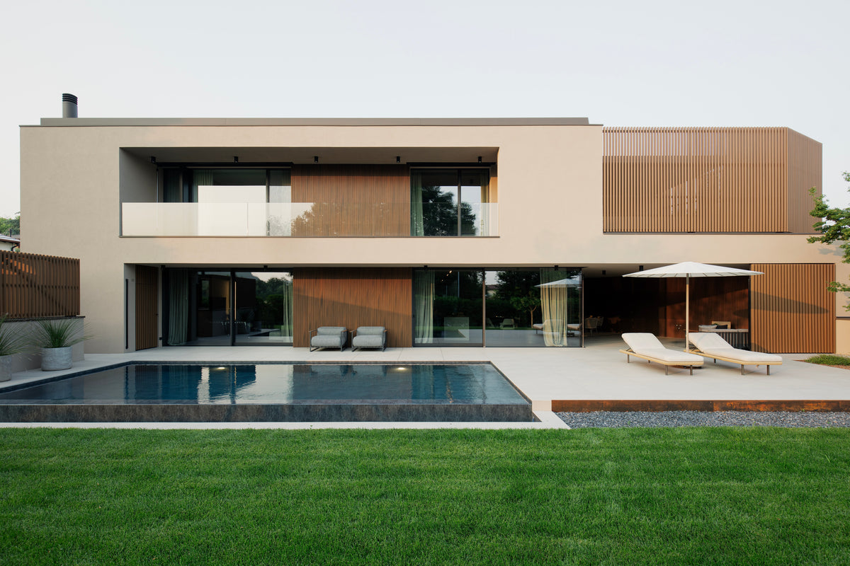 Prospetto della villa contemporanea con piscina lineare e ampio giardino