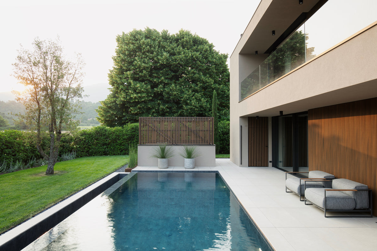Vista longitudinale della piscina tra i volumi della casa e il patio coperto