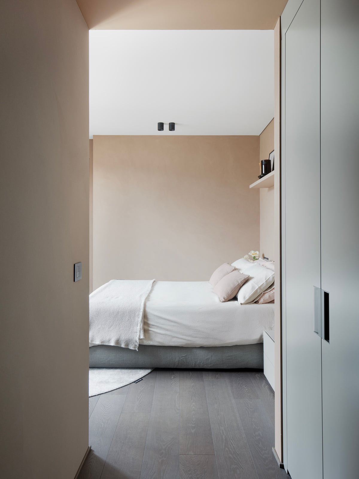 Vista della camera con armadiature integrate e letto tessile