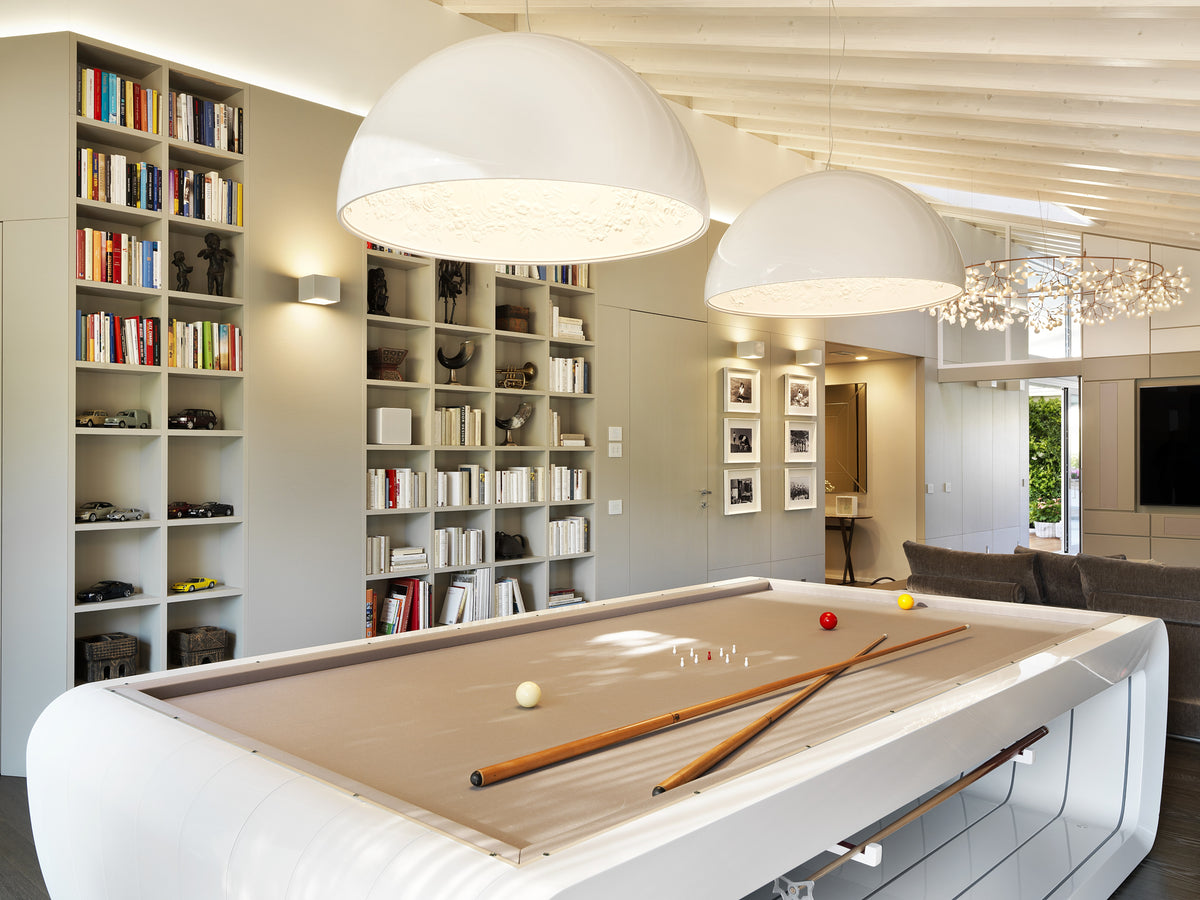 Open space con biliardo, libreria a parete su misura e lampade sospese di grandi dimensioni