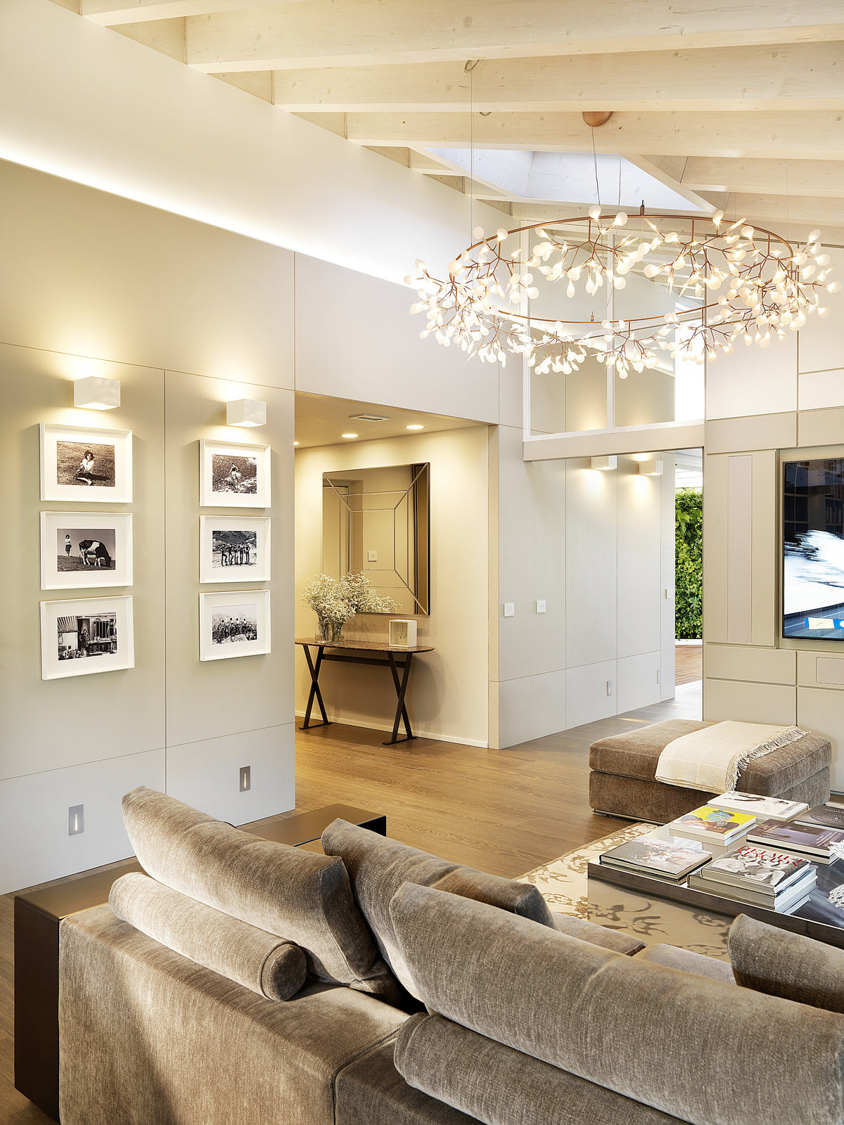 Living dell’attico con divano modulare, lampadario scenografico e progetto residenziale su misura