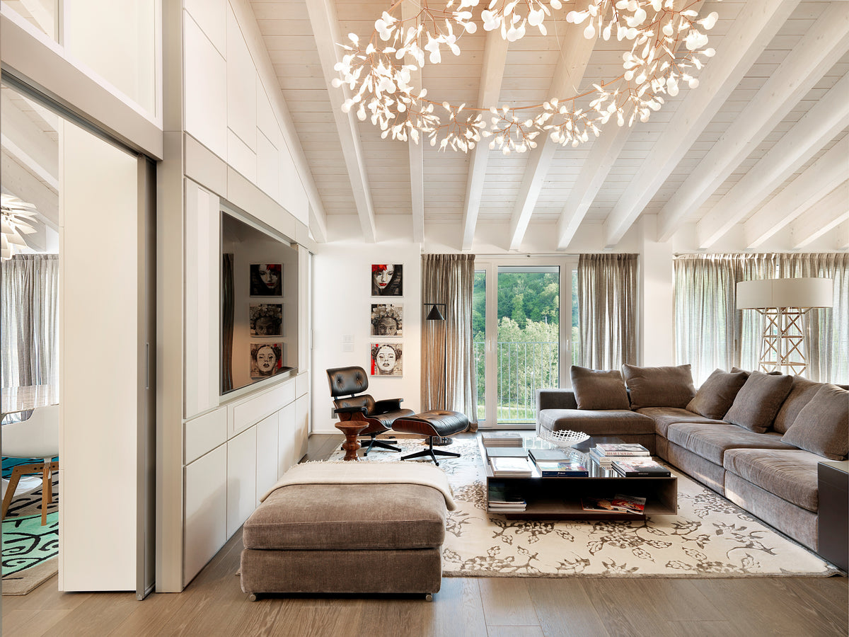 Soggiorno con divano angolare, parete TV integrata, illuminazione decorativa e passaggio verso la cucina
