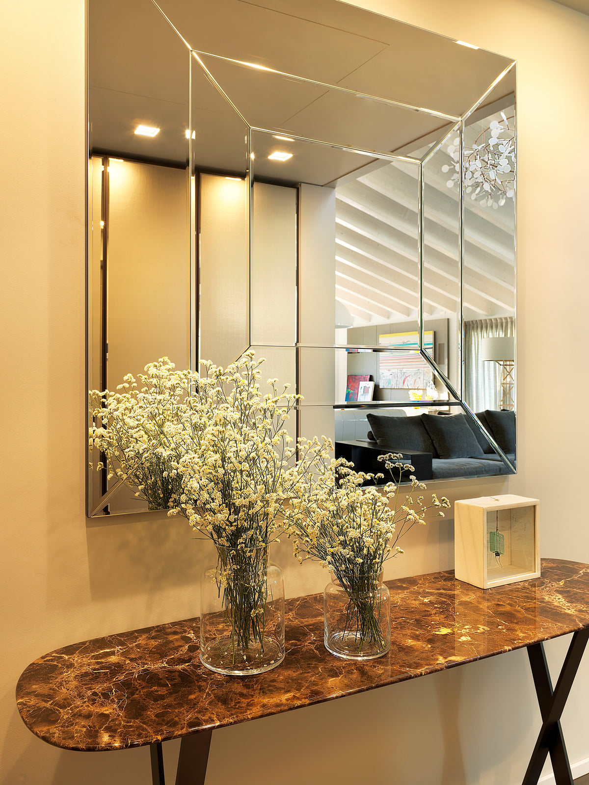 Consolle in marmo marrone con grande specchio di design e dettagli riflettenti all’ingresso della zona giorno