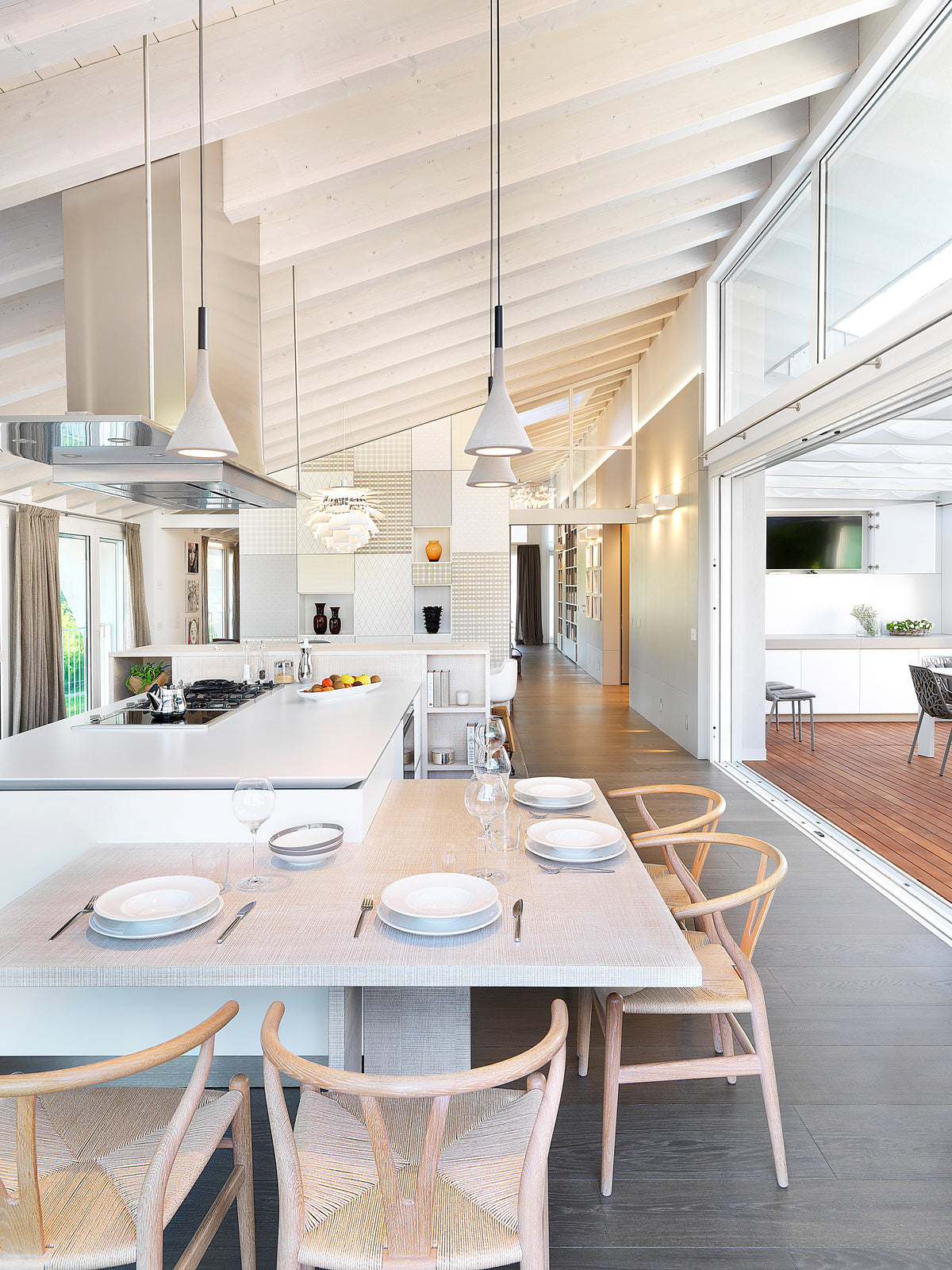 Cucina con isola e tavolo da pranzo integrato in un attico contemporaneo progettato su misura