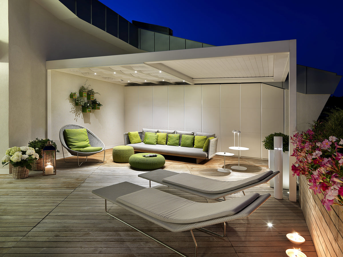 Terrazza esterna dell’attico con arredi outdoor, area lounge e illuminazione scenografica serale
