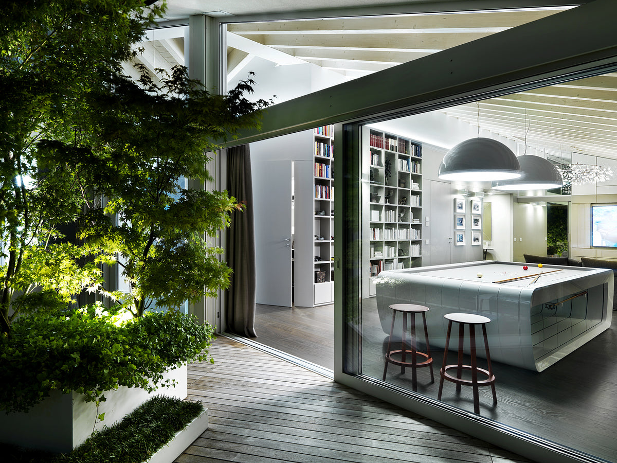 Vista serale della zona giorno con biliardo dalla terrazza, con pergola, angolo verde e deck in legno