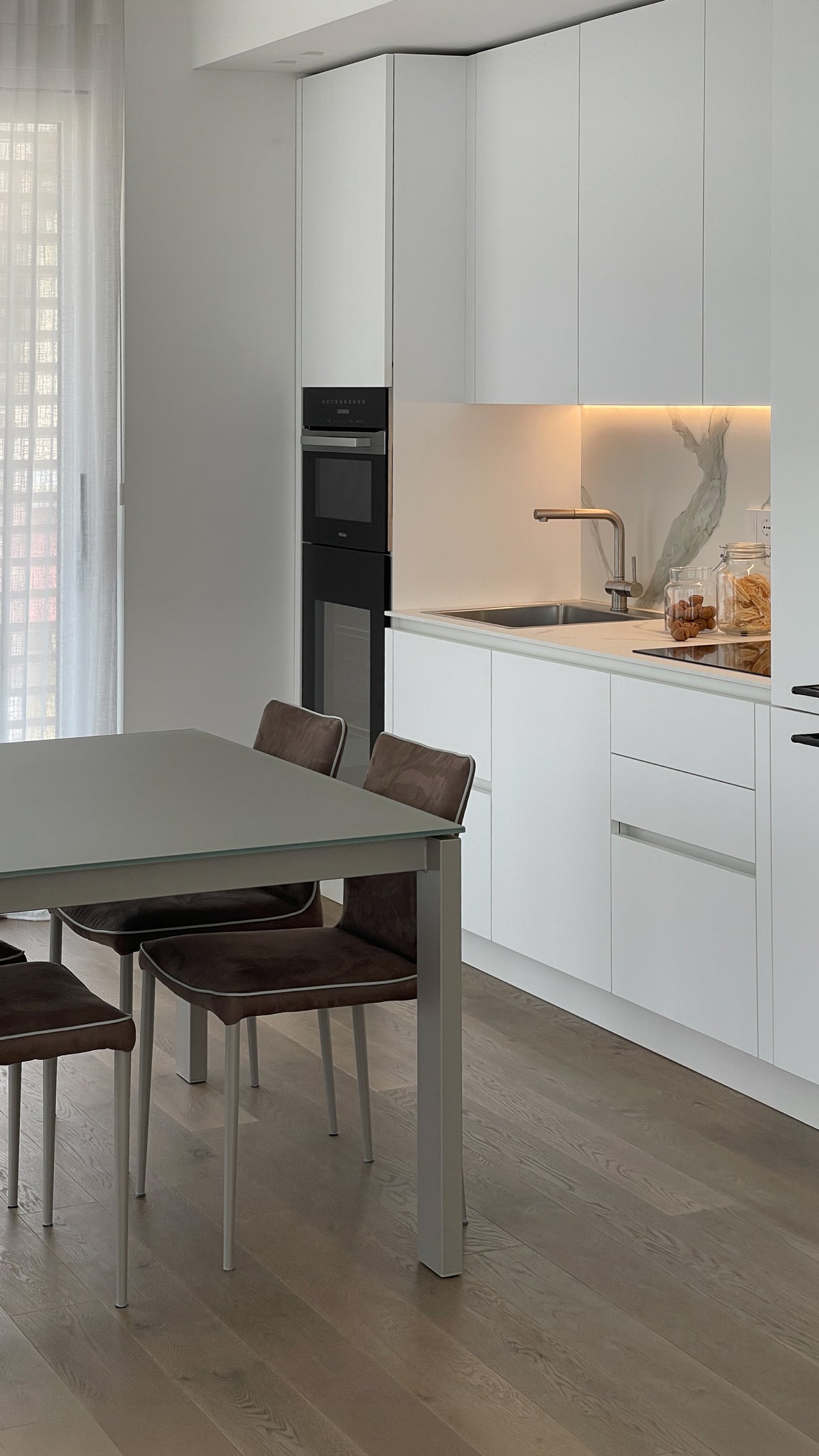 Cucina su misura bianca integrata nell’open space di un attico contemporaneo sul Lago di Garda