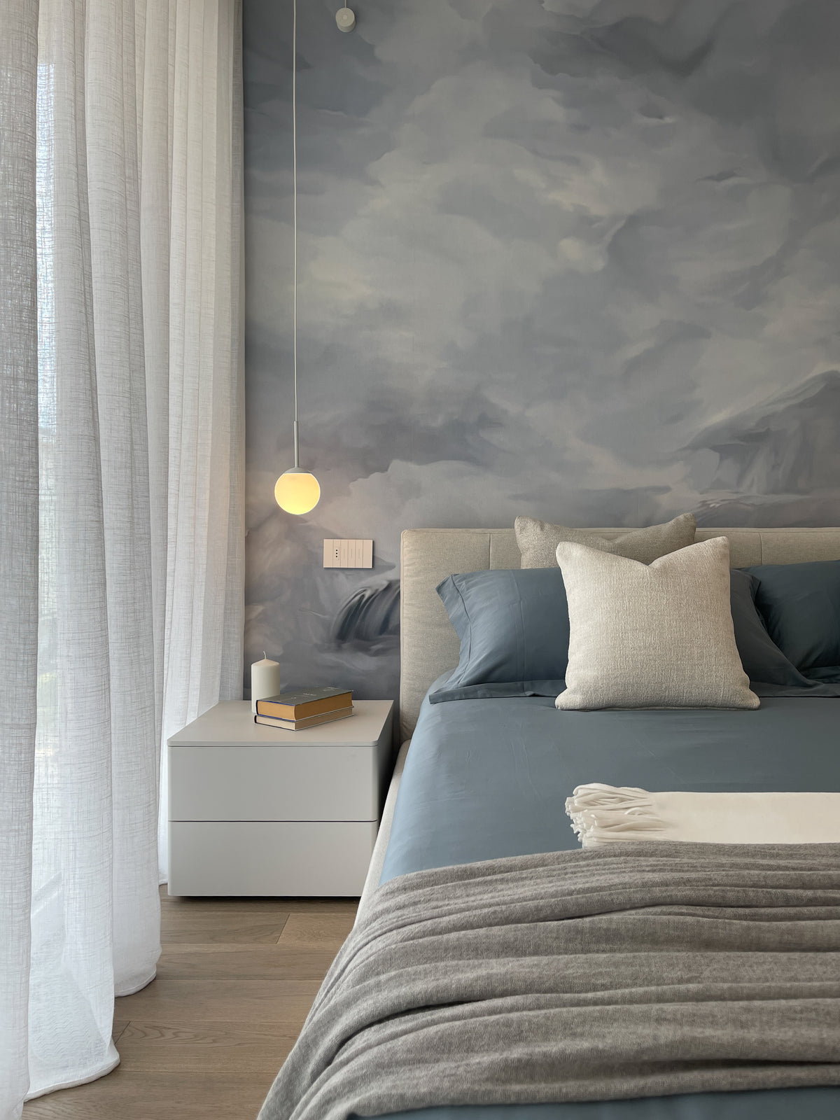 Interior design della camera da letto di un attico sul Lago di Garda con carta da parati panoramica nei toni del grigio e azzurro