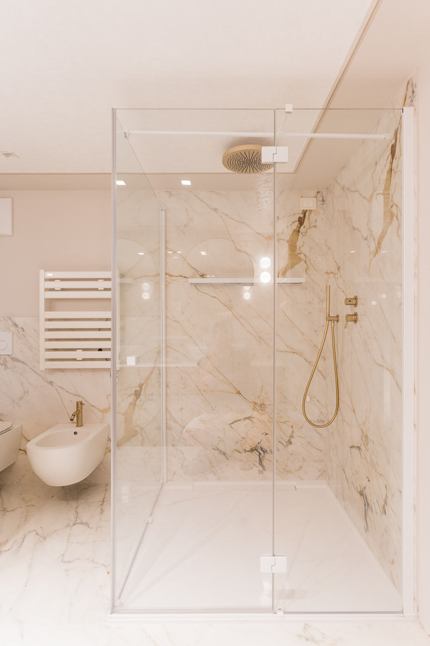 Doccia walk-in in marmo con soffione integrato e venature calde