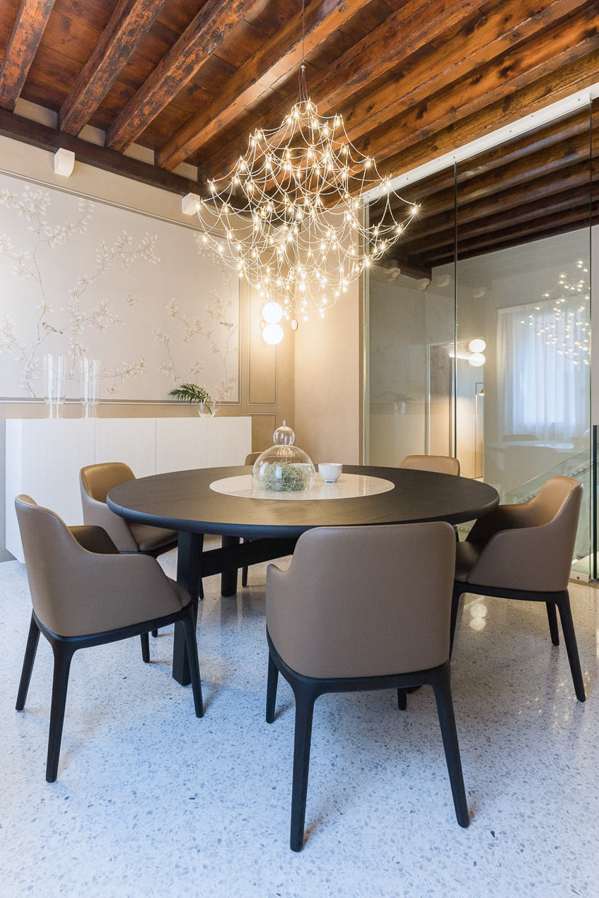 Progetto di interior design per sala da pranzo con tavolo rotondo in legno, sedute imbottite e luce decorativa