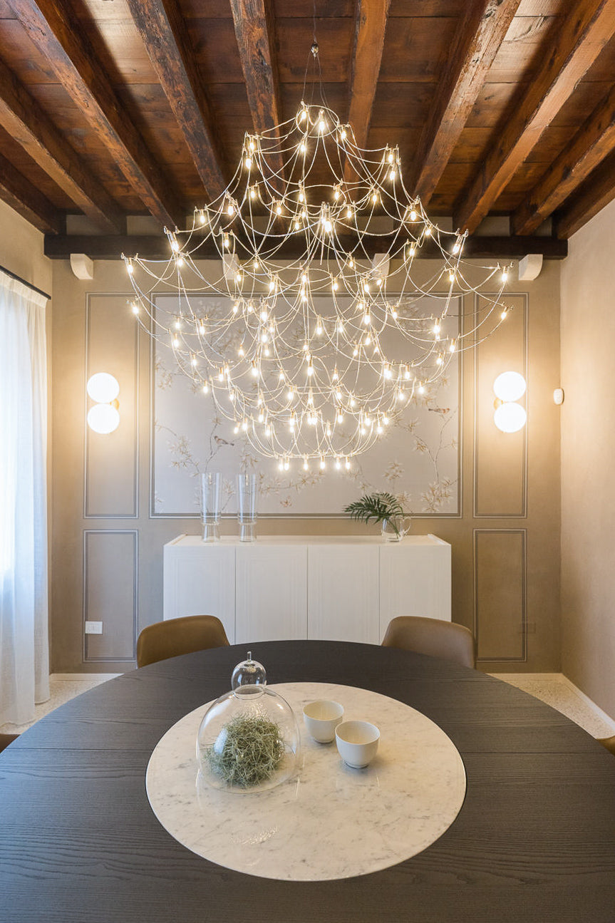 Sala da pranzo con chandelier contemporaneo e dialogo tra arredi e soffitto storico