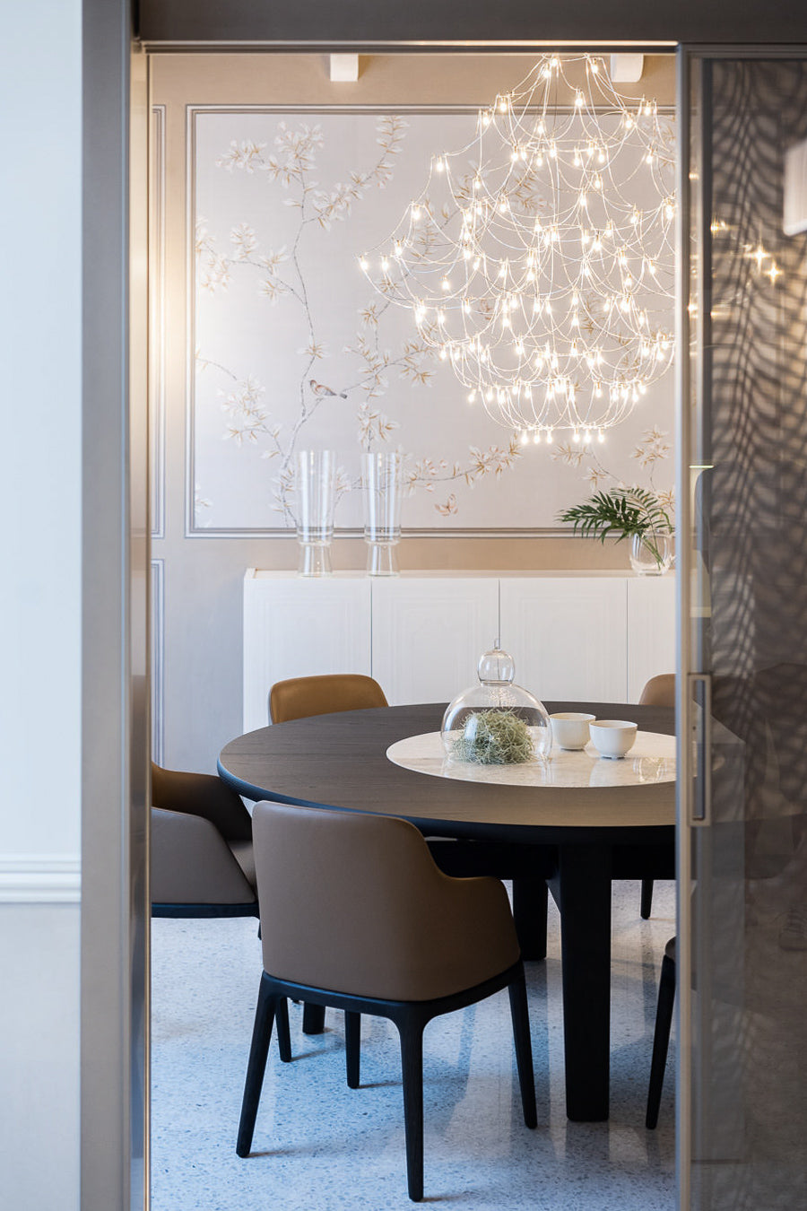 Vista della sala da pranzo con tavolo rotondo e lampadario dal passaggio interno verso la cucina