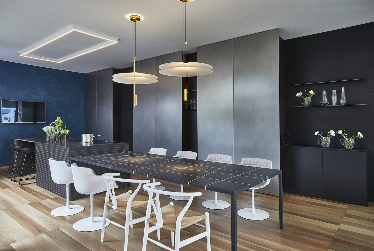 Zona pranzo contemporanea con tavolo scuro, sedute bianche e contenitori integrati