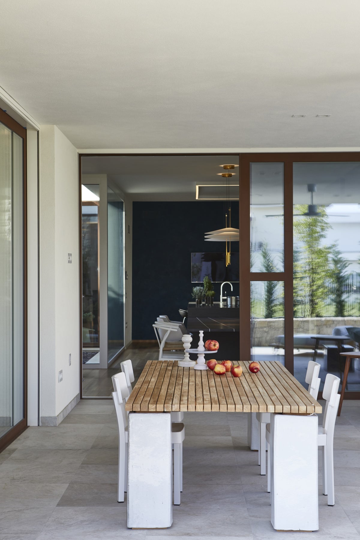 Dettaglio del porticato con tavolo outdoor in legno e collegamento diretto con gli interni