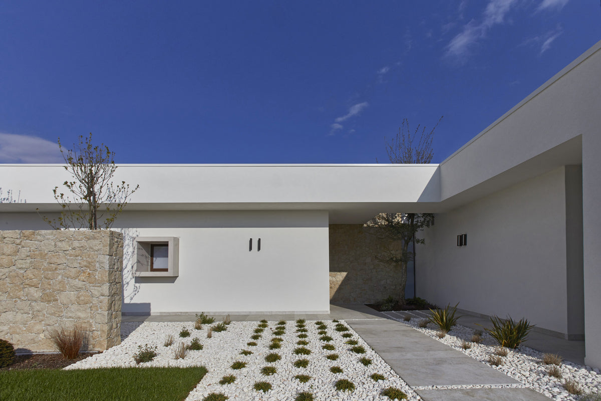 Cortile d’ingresso della casa privata con architettura lineare e pavimentazione drenante