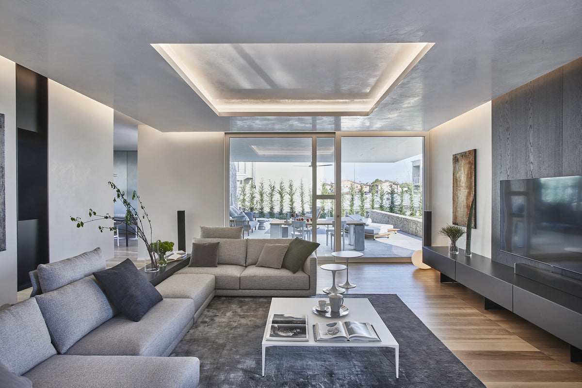 Soggiorno contemporaneo con divano componibile, soffitto luminoso e aperture sullo spazio esterno