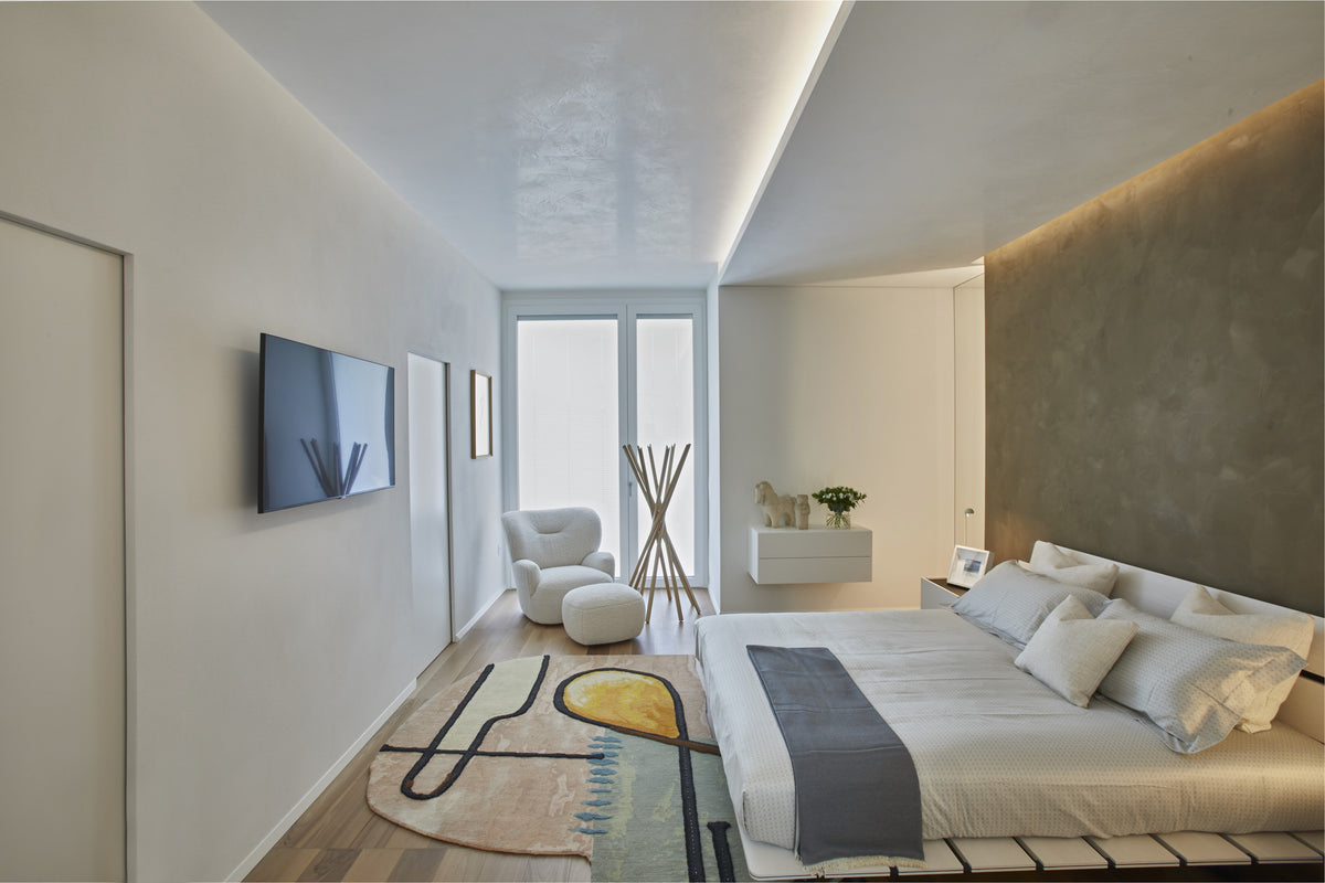 Zona notte con letto in legno, parete materica e tappeto di design