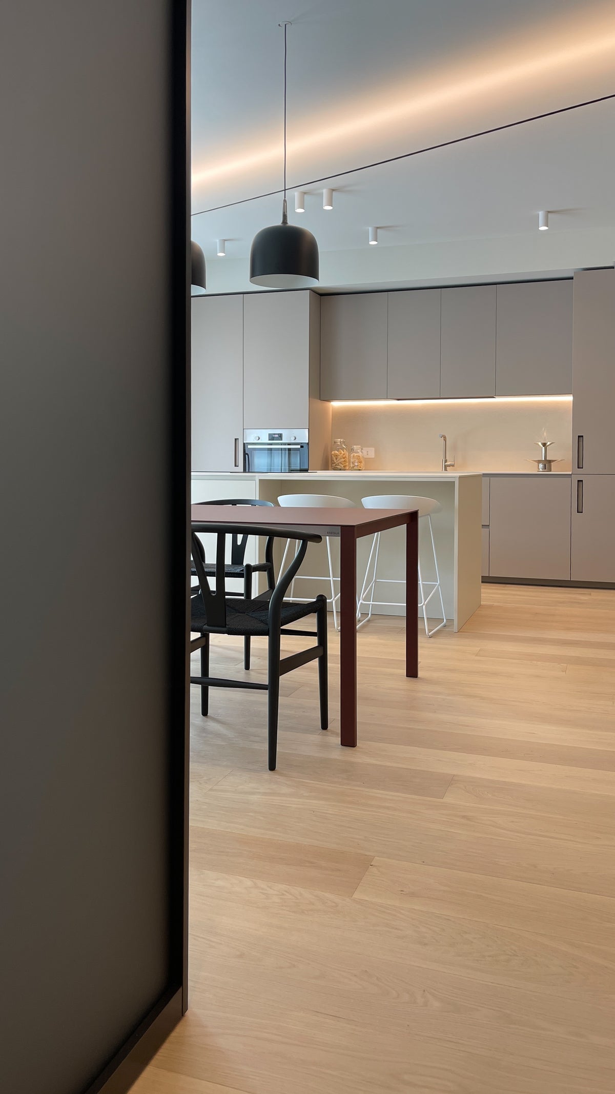 Vista prospettica della zona giorno con cucina integrata nella parete attrezzata e tavolo da pranzo