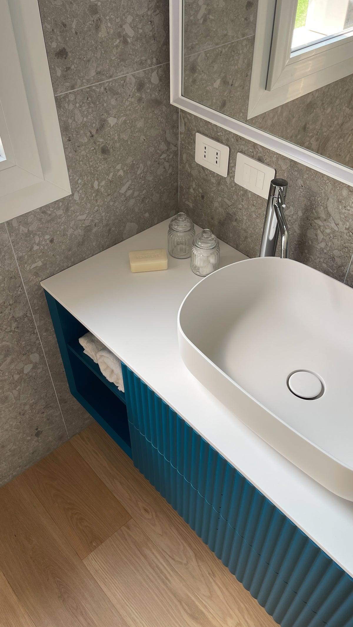 Dettaglio del lavabo da appoggio e del mobile bagno blu ottanio con frontali lavorati