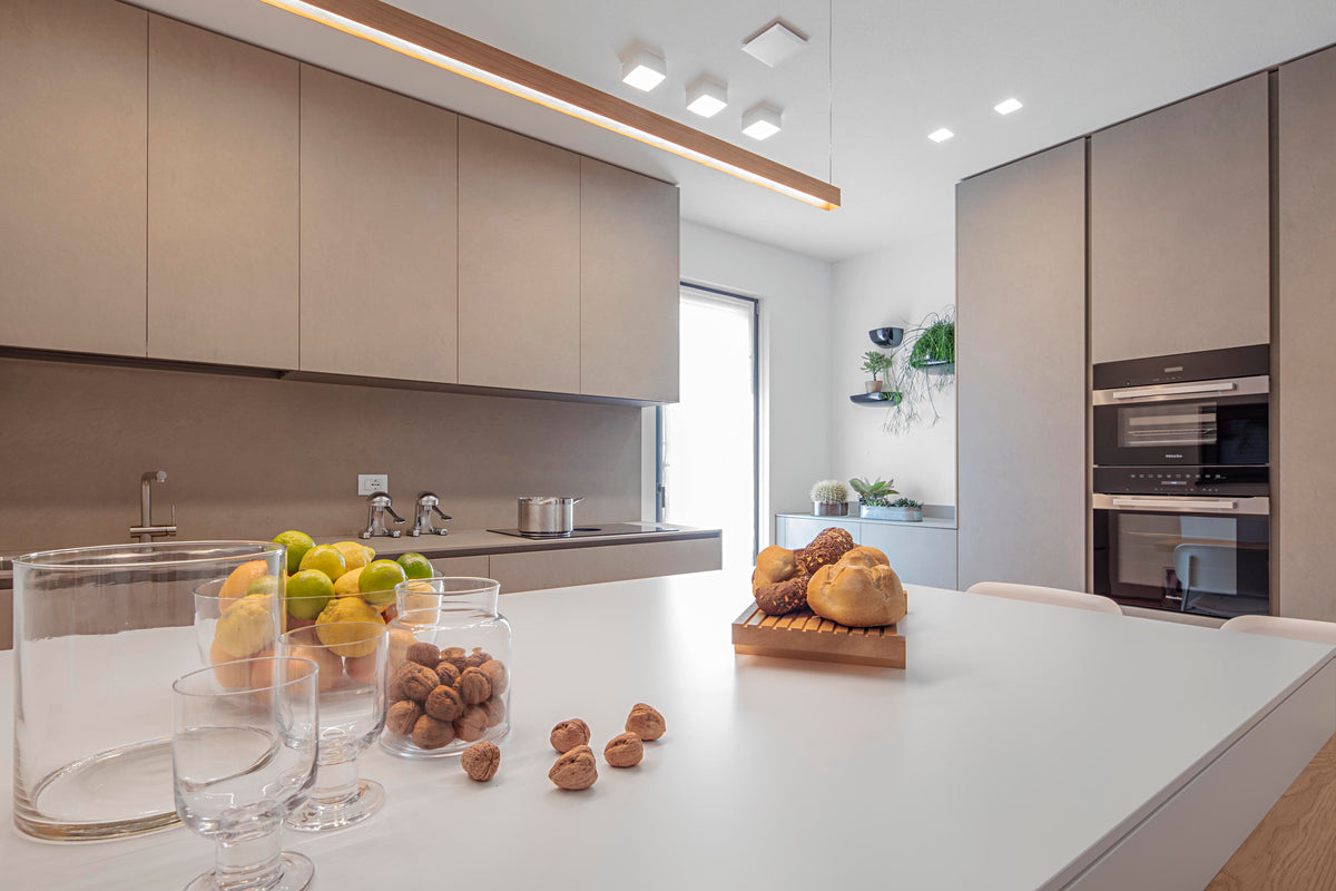 Cucina con isola bianca e finiture materiche, progettazione su misura per spazio contemporaneo