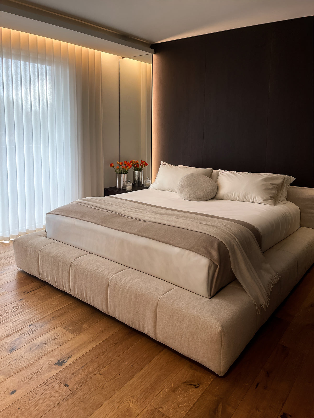 Camera padronale contemporanea con letto imbottito e parete in legno scuro progettata su misura