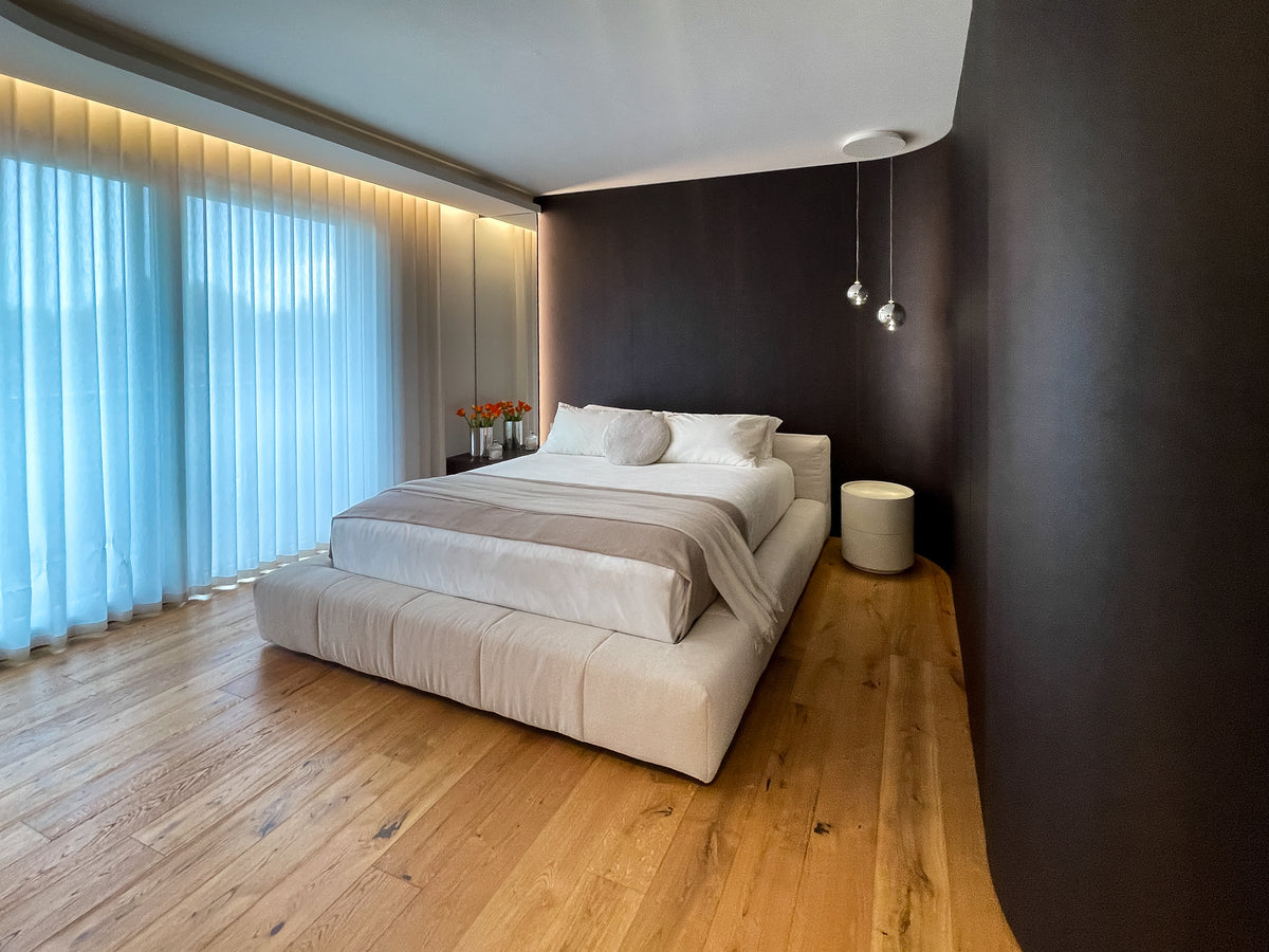 Progetto su misura della camera padronale con letto imbottito, boiserie e armadiatura curva integrata