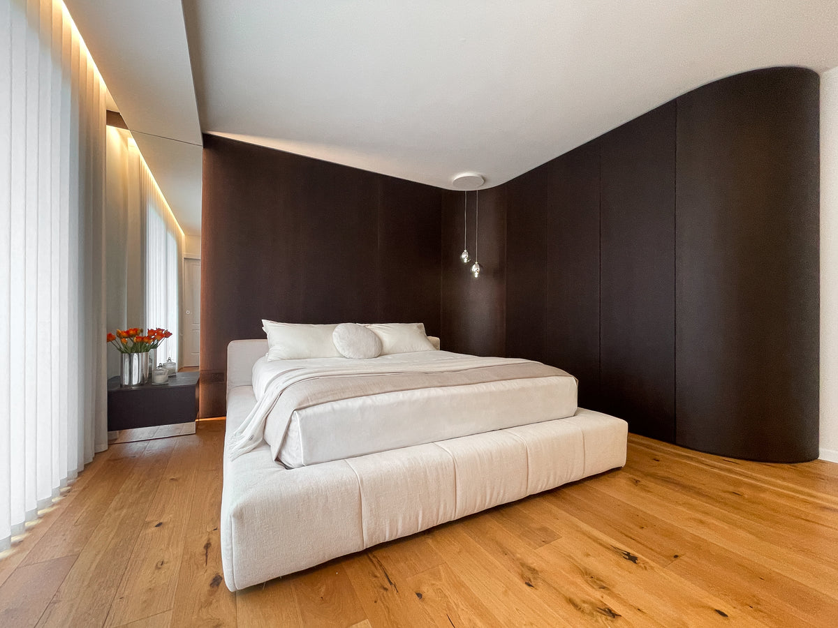 Camera da letto con armadiatura curva su misura che avvolge la parete e prosegue nella boiserie dietro al letto