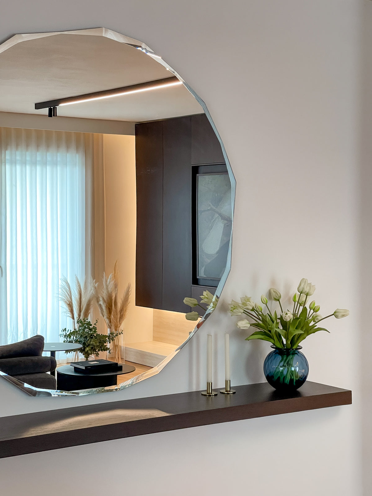 Specchio decorativo irregolare con mensola in legno scuro e dettaglio riflesso del living