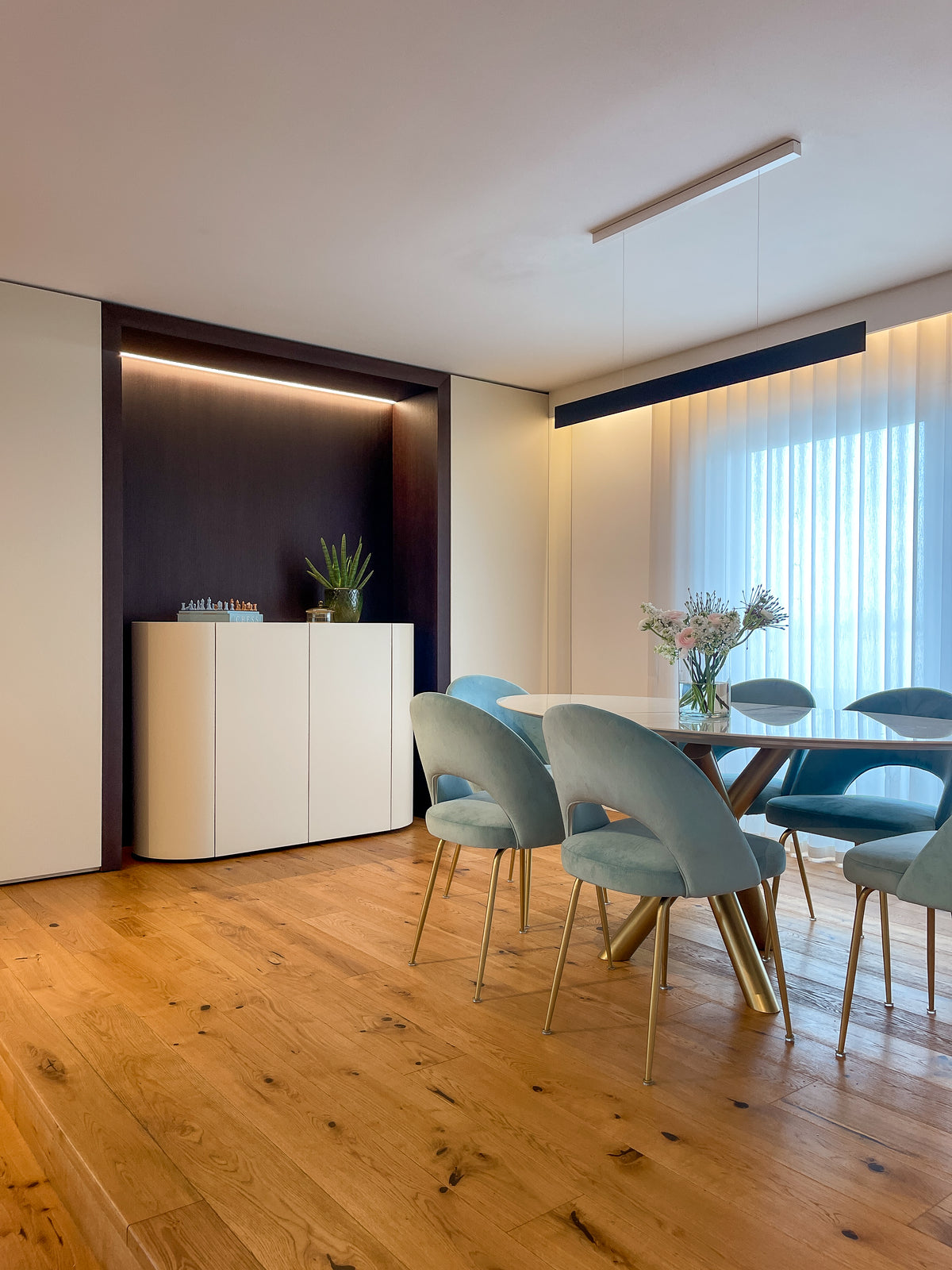 Sala da pranzo contemporanea con tavolo, sedie azzurro polvere e madia integrata nella parete attrezzata