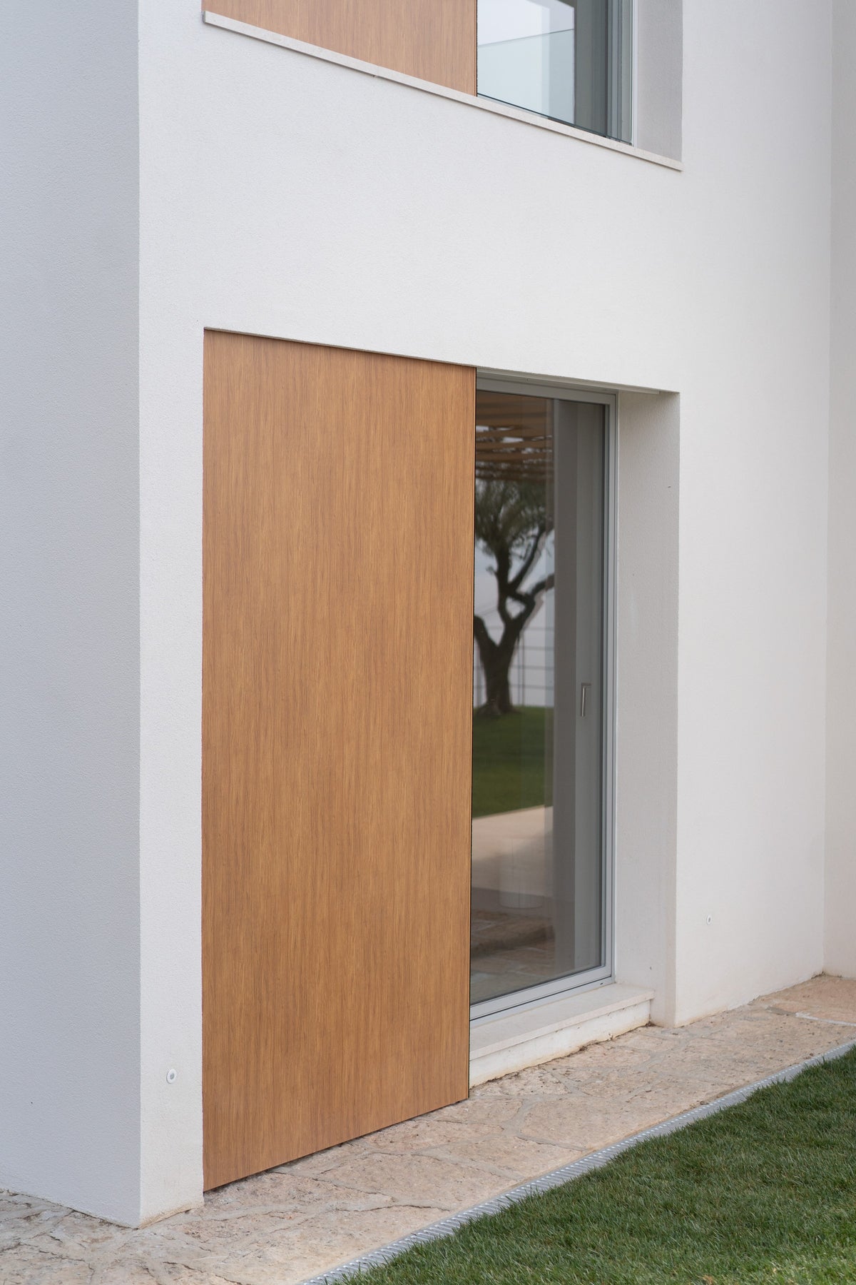 Dettaglio di una finestra con facciata chiara e inserto verticale in legno