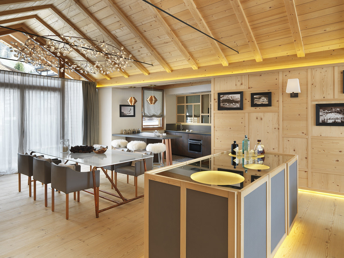 Cucina e sala da pranzo open space dello chalet con isola centrale e boiserie in legno su misura
