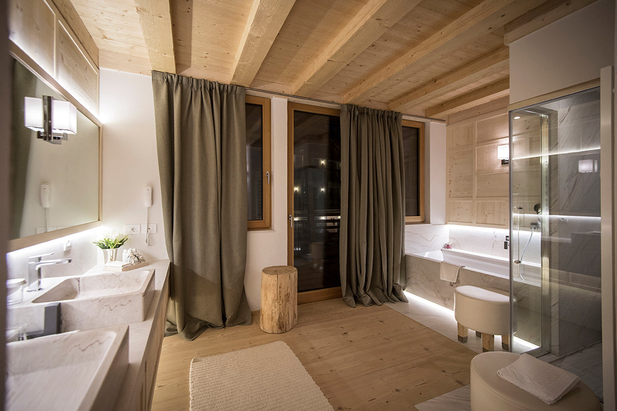 Bagno dello chalet privato con doppio lavabo in marmo, vasca e doccia, superfici chiare e falegnameria integrata