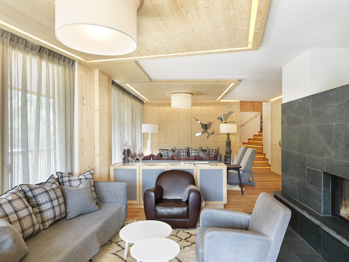Zona relax in lounge con camino in pietra, divani e poltrona in pelle, in un ambiente caldo e contemporaneo