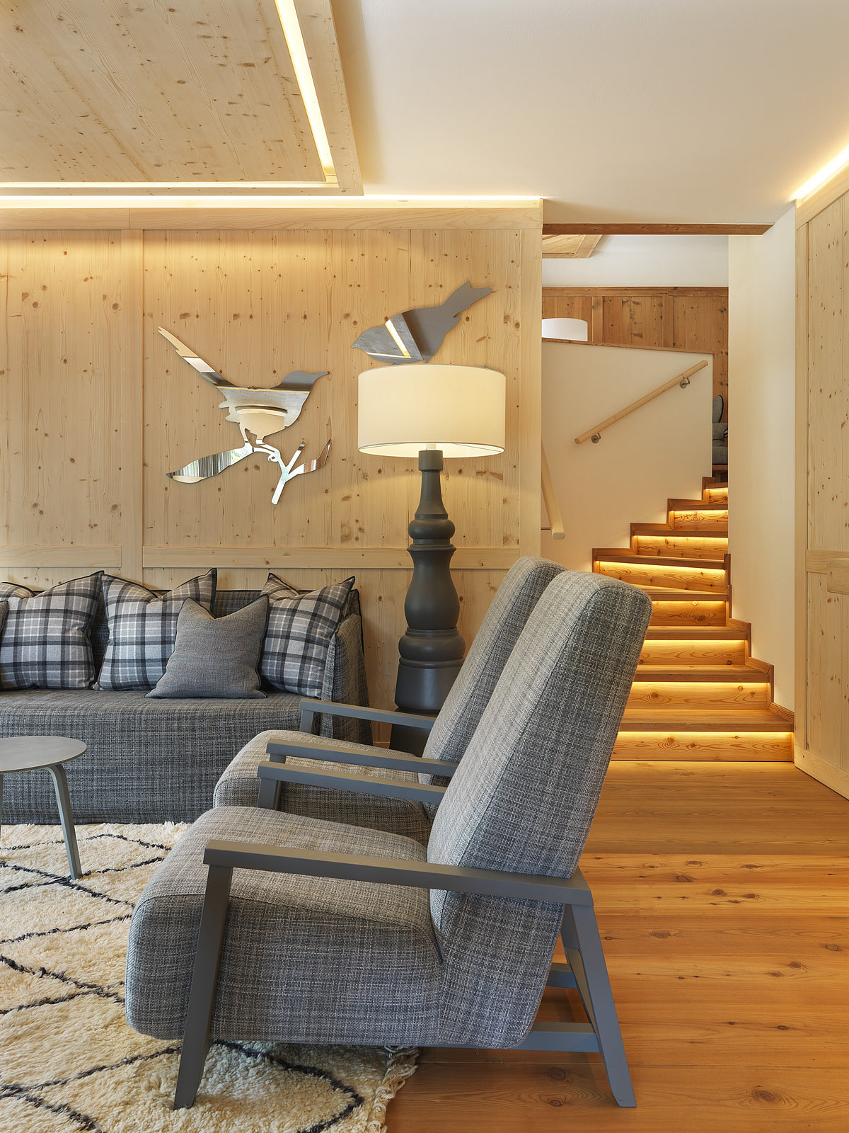 Angolo conversazione con poltrone, divano e scala in legno con illuminazione integrata nella pedata