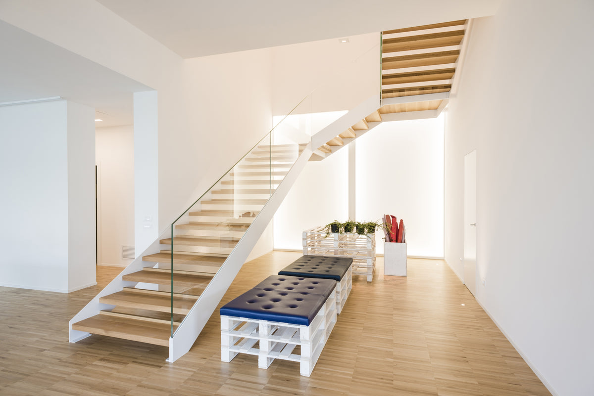 Vista interna con sedute su pallet e scala interna con struttura leggera e pedate in legno, elemento architettonico centrale nello spazio