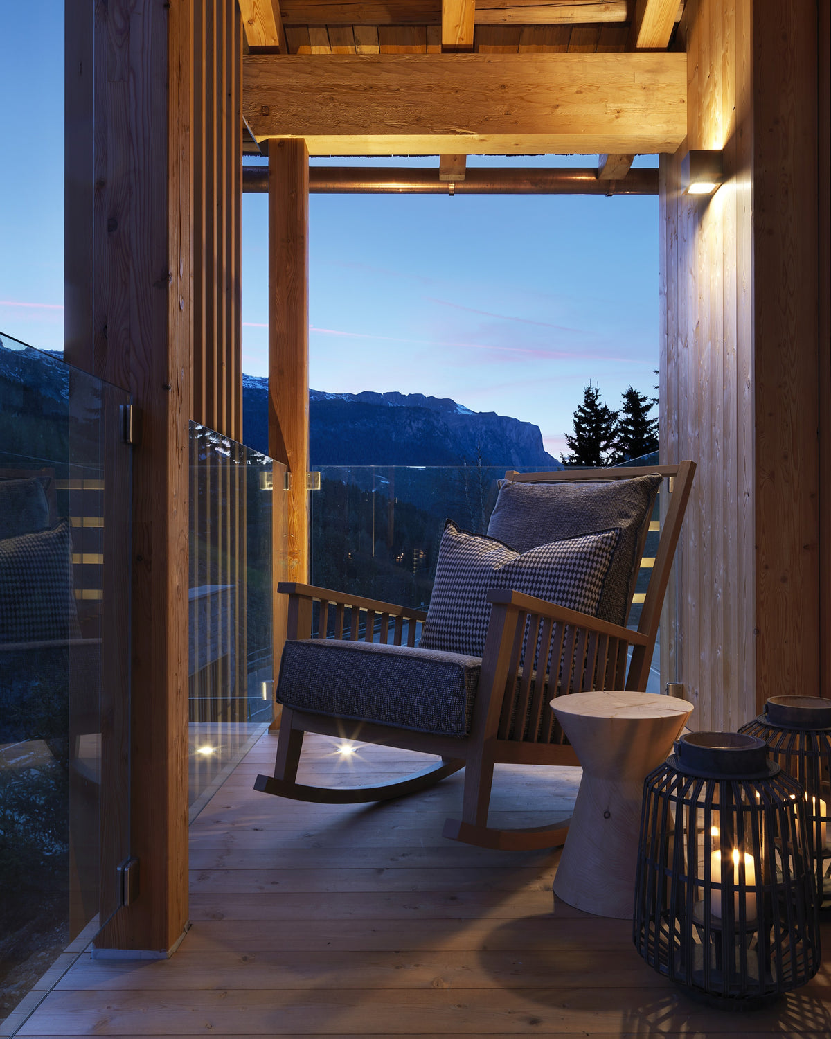 Particolare portico con poltrona lounge, tavolino in legno e lanterna in ambiente alpino