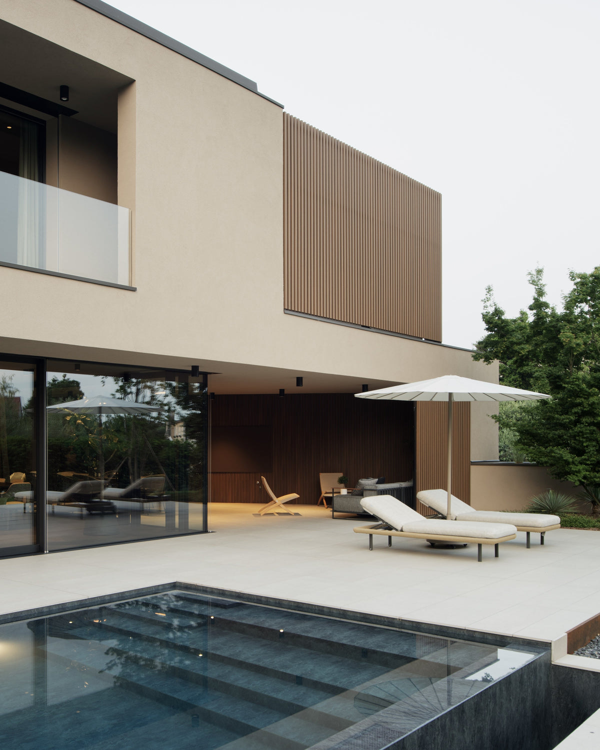 Villa contemporanea con piscina rettangolare, patio e facciata in intonaco e legno