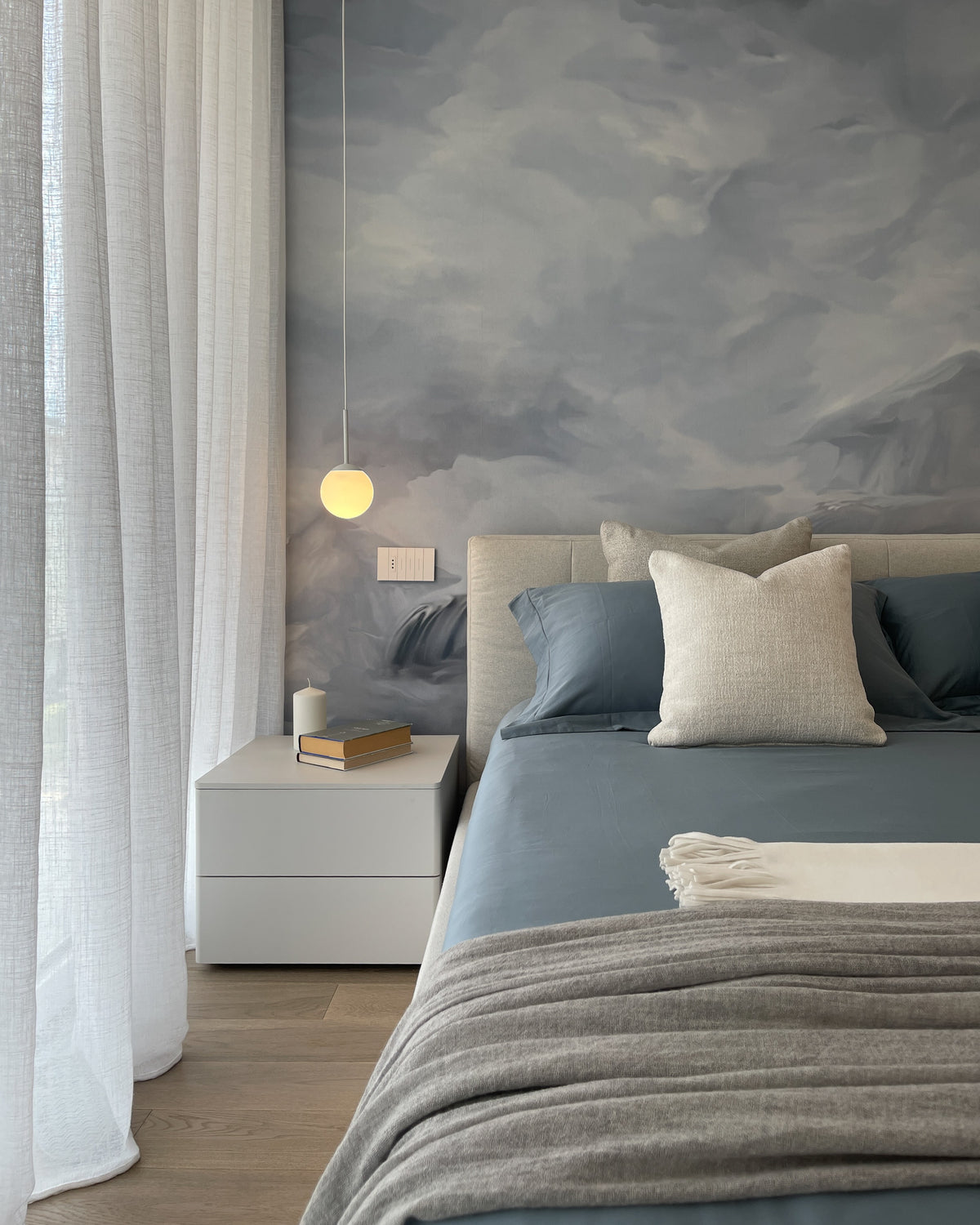 Camera da letto luminosa con carta da parati panoramica, letto imbottito e palette nei toni azzurri