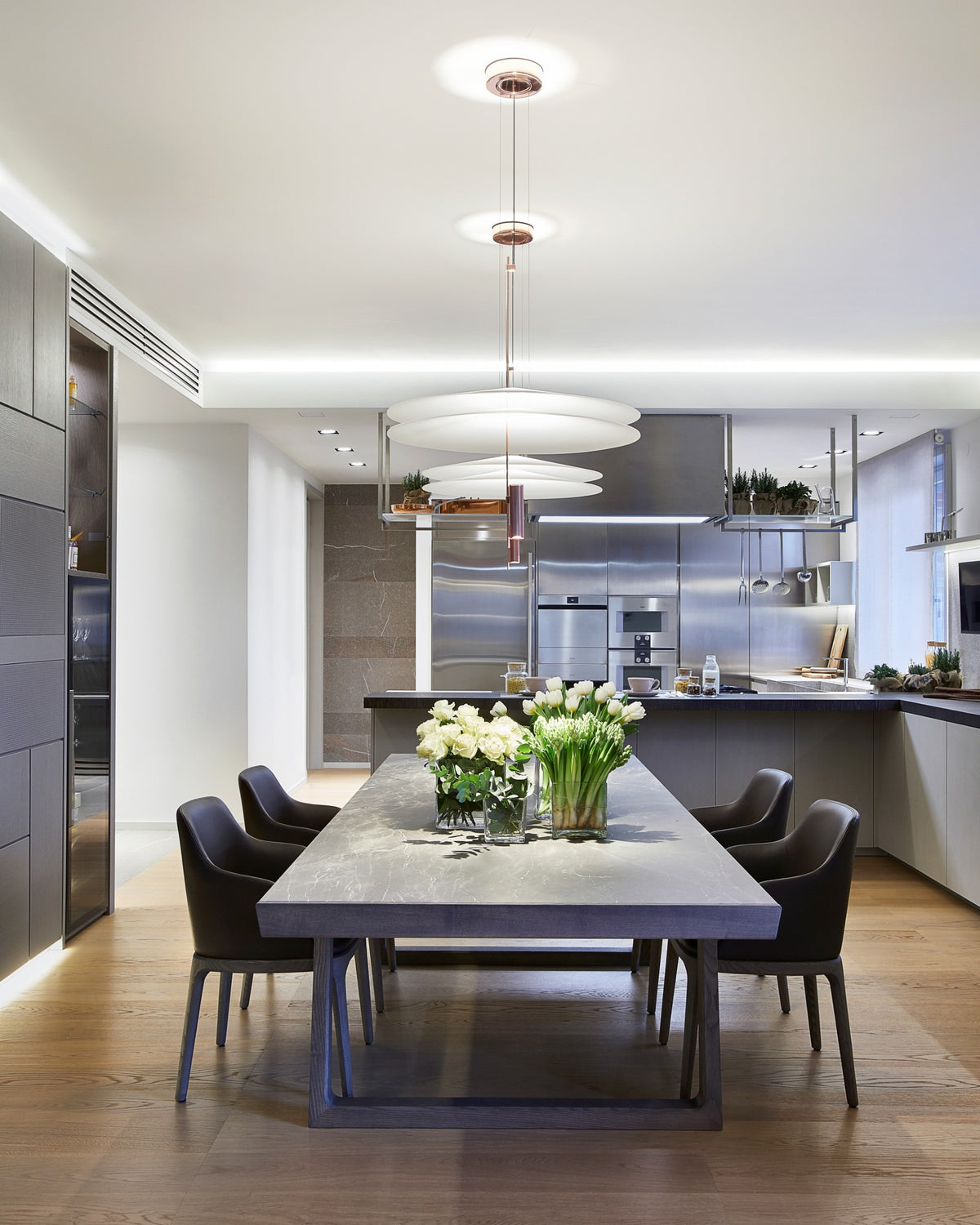 Dettaglio della Zona pranzo contemporanea con tavolo materico, lampade sospese e cucina open space