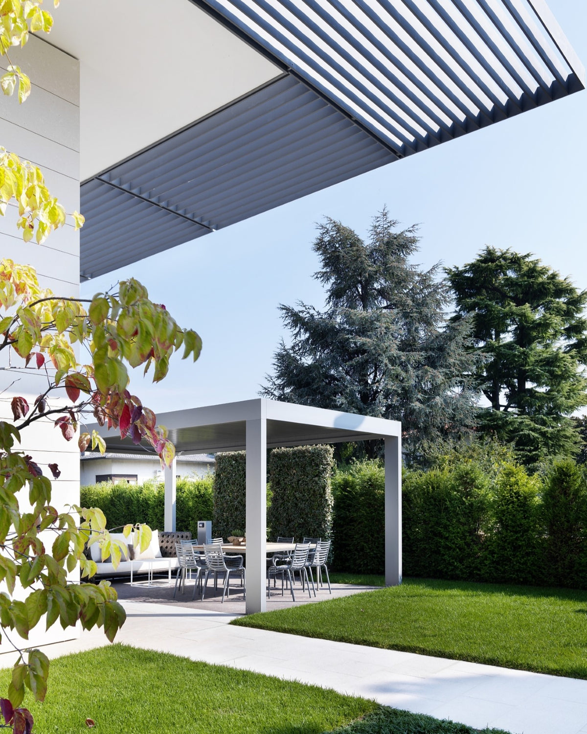 Vista dell'area relax outdoor con pergola bioclimatica e giardino curato