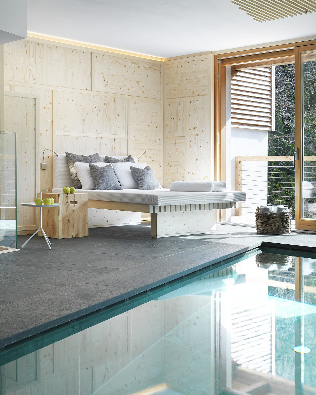 Dettaglio della piscina interna con bordo in pietra e area relax in uno spazio wellness dall’estetica essenziale
