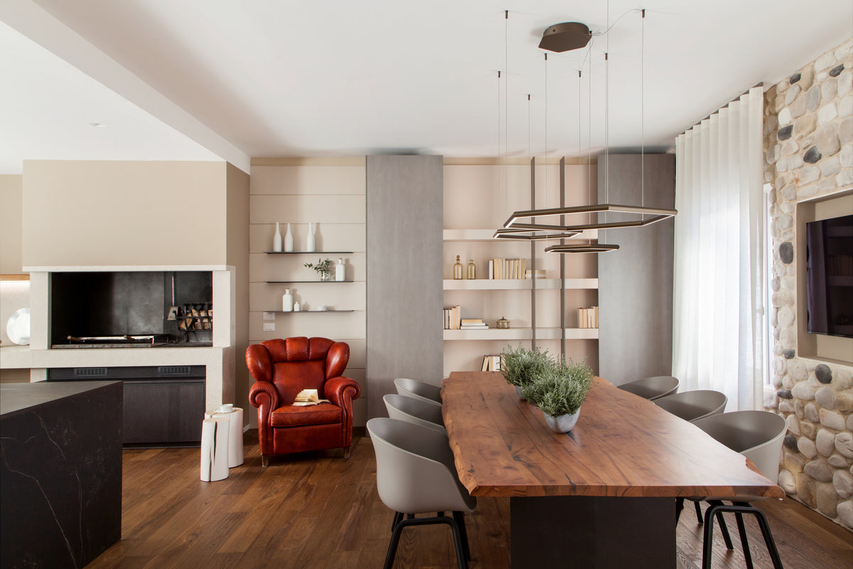 Zona pranzo con grande tavolo in legno, sedute grigie, camino integrato e arredi di design in una casa privata contemporanea