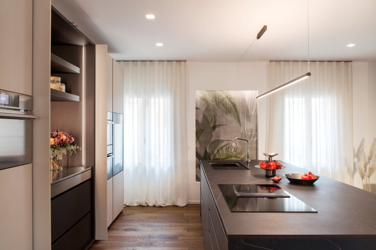 Cucina con isola centrale, composizione lineare e modulo con ante rientranti in un progetto di interior design residenziale