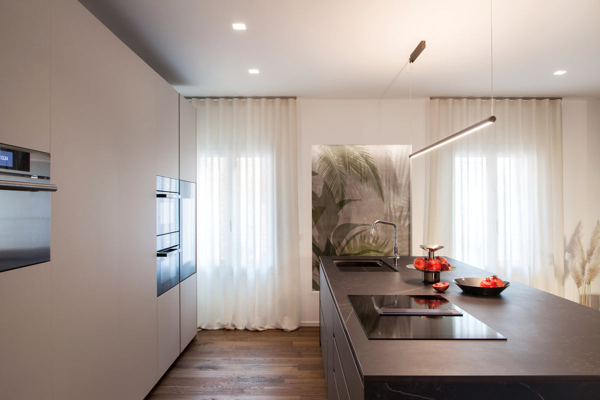 Cucina contemporanea con isola scura, colonne integrate e tende filtranti a tutta altezza