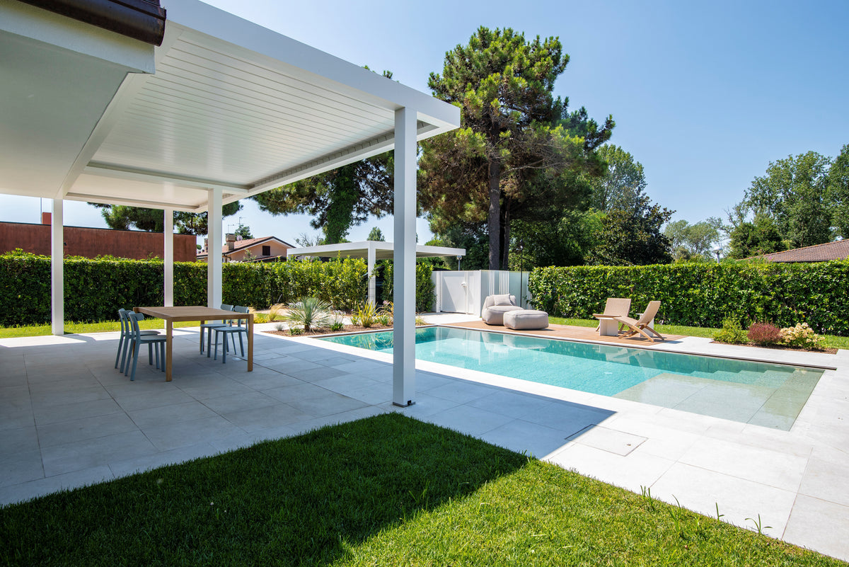 Spazi outdoor con piscina, portico coperto e giardino nella ristrutturazione di una casa anni ’70 ad Albarella