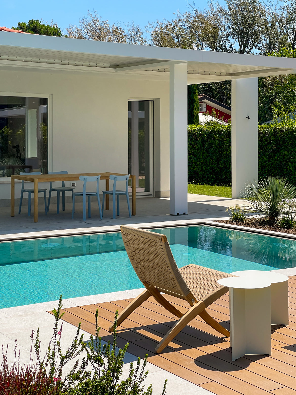 Progetto outdoor ad Albarella con piscina, pergola bioclimatica, zona pranzo coperta e area relax su pavimentazione in legno